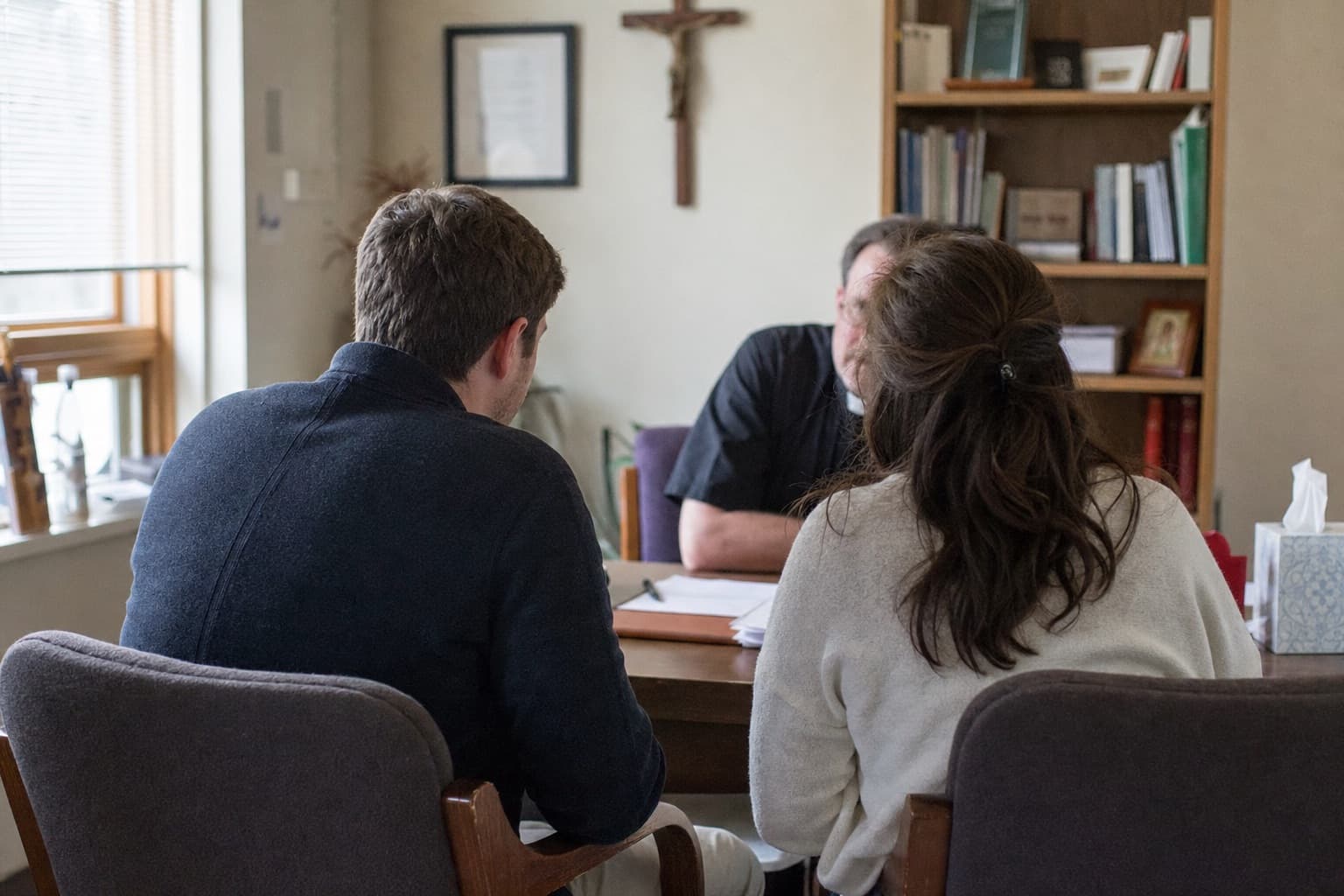 A couple meeting a priest across his desk