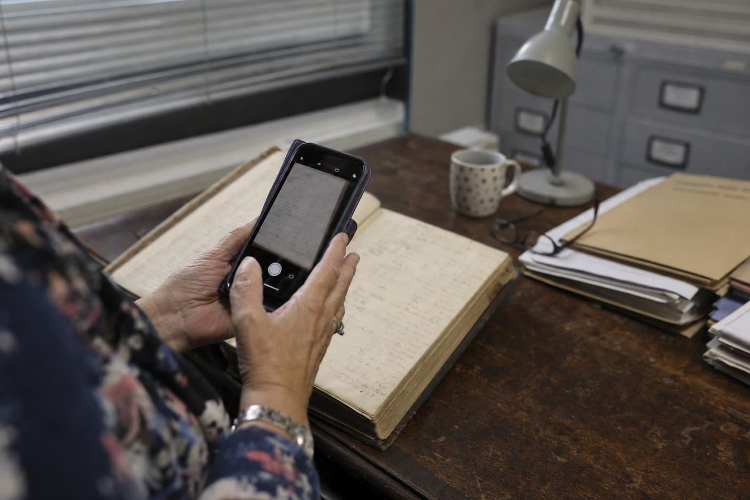 A parish secretary photographing a page of an old register with her phone
